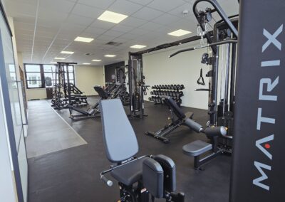 Trainingsfläche mit Kabelzugstationen, Gewichtsscheiben und Holz-Raumteiler bei LSZ Sportphysiotherapie